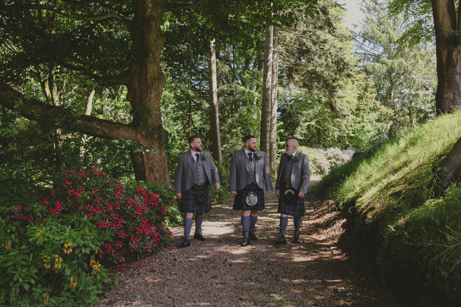 Groom and his groomsmen walk in woodlands at Norwood Hall Hotel